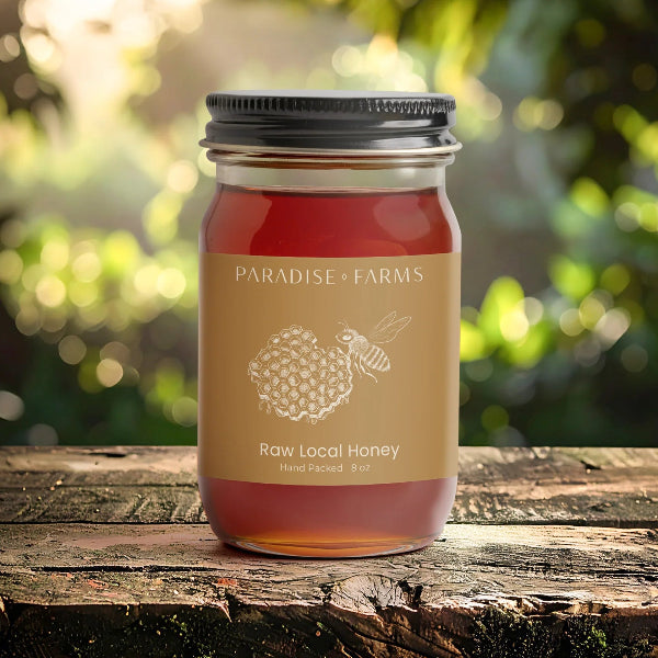 Jar of Paradise Farms raw local honey on a wooden surface with a blurred natural background